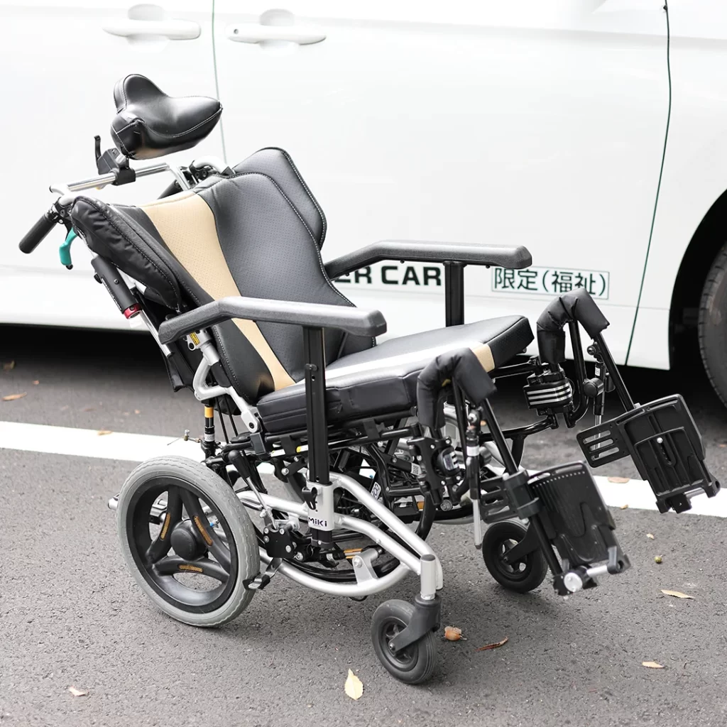 リクライニング車椅子、グレーとベージュのツートーンシート、調整可能なヘッドレストと足置き、ティルト機能付き